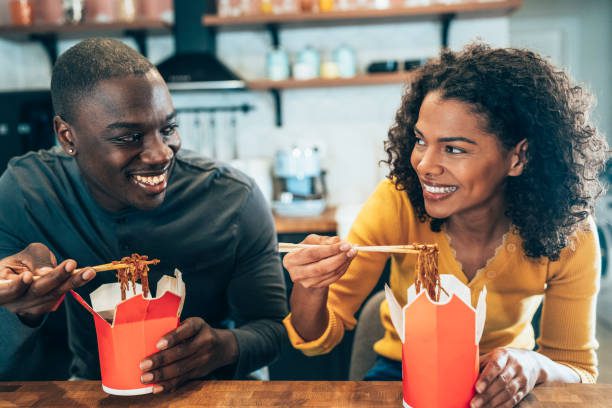 Afro-american Couple eating take-out Chinese food at home